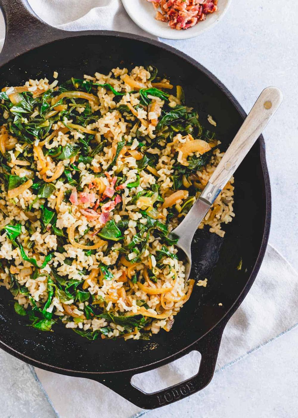 Southern spicy collard greens recipe tossed with rice in a skillet with a serving spoon.