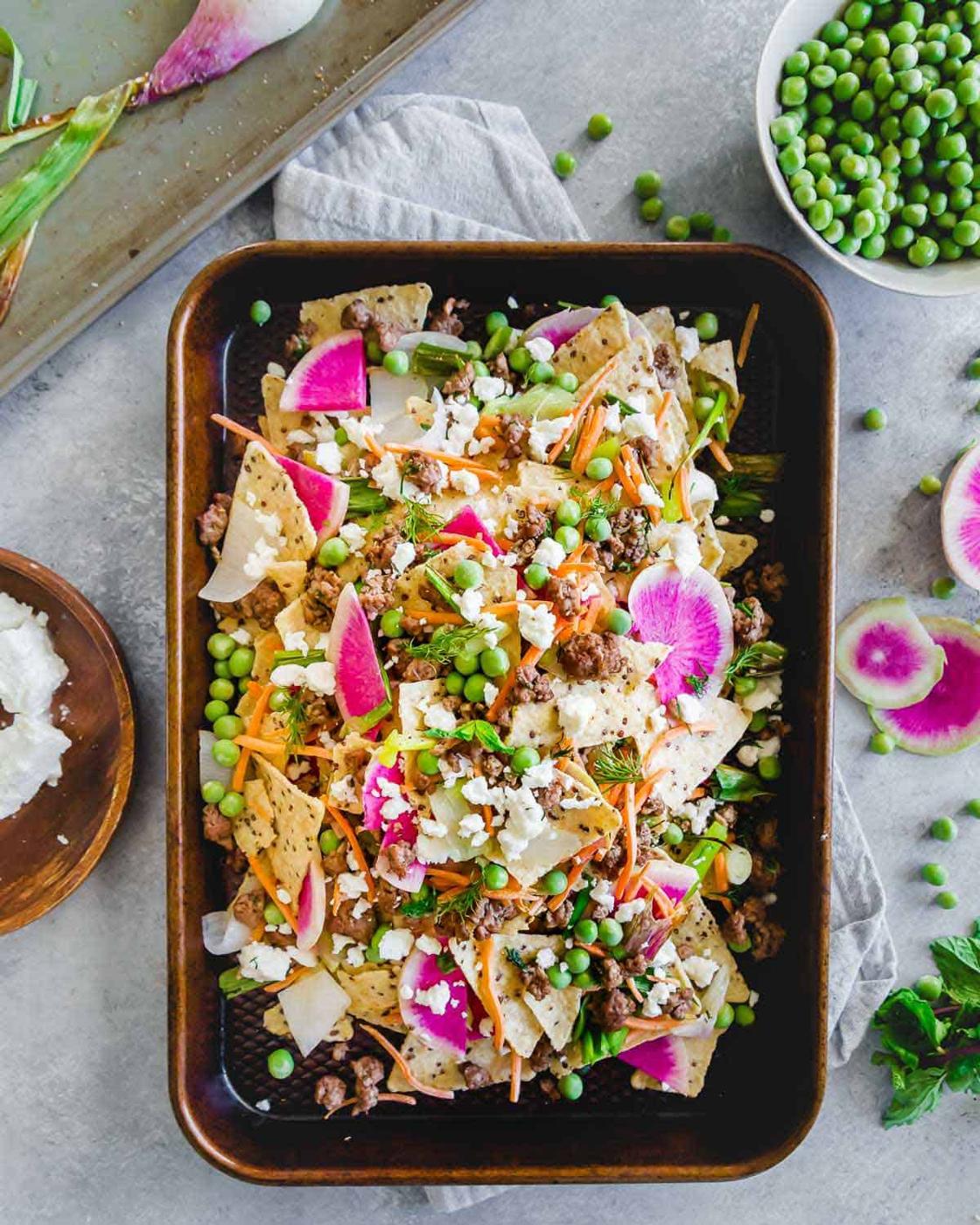 These ground American lamb nachos with carrots, onions, peas and radishes are topped with crumbled feta cheese for a bright and fresh spring take on nachos. Enjoy them straight off the baking sheet for an easy seasonal dinner or appetizer.
