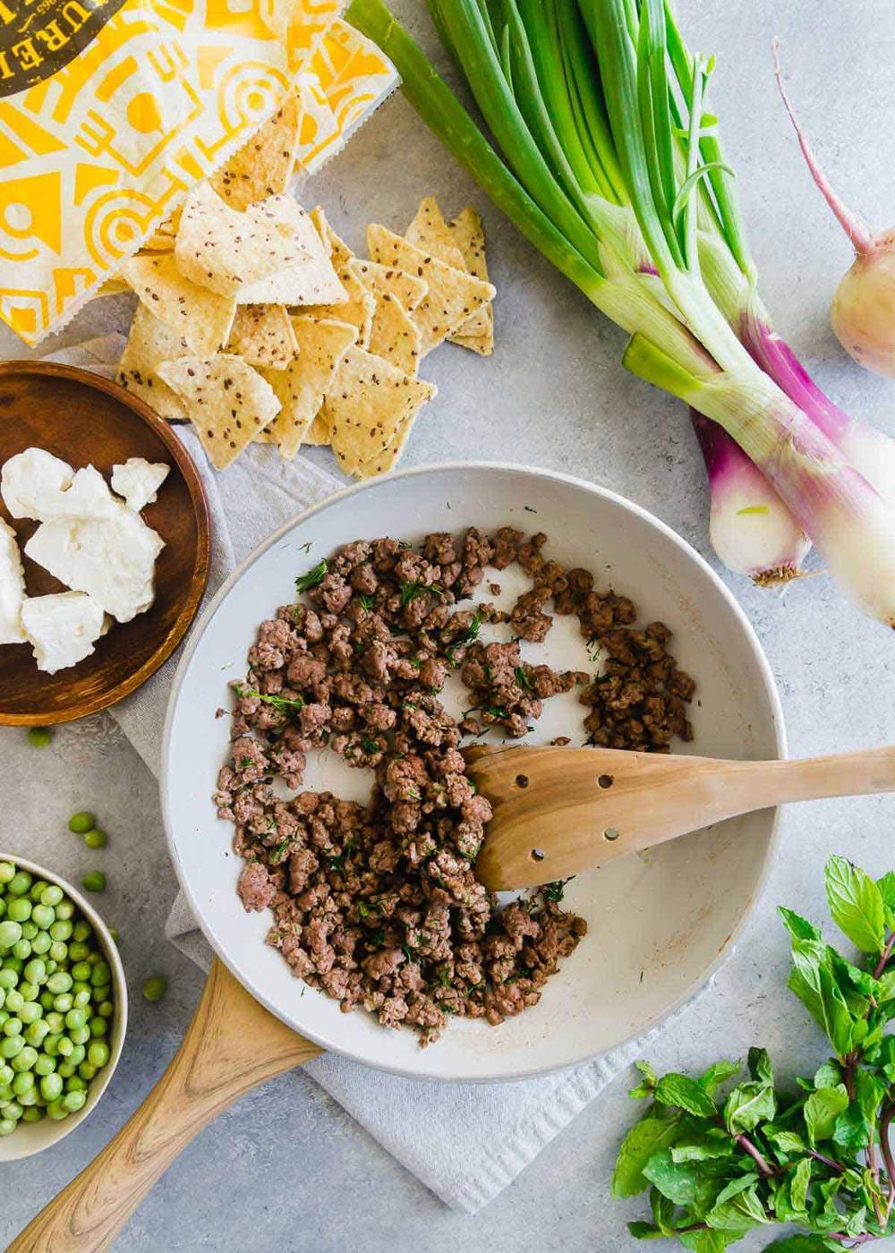 lamb nachos use ground American lamb with a bunch of early spring vegetables and lots of crumbled feta cheese for a fun seasonal twist to traditional nachos.