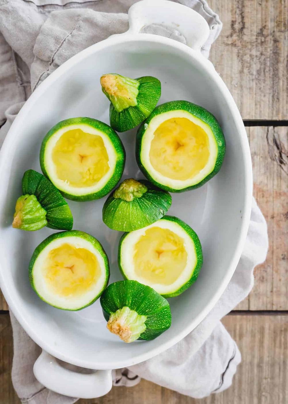 Hollowed out round zucchini squash in a baking dish to be stuffed.