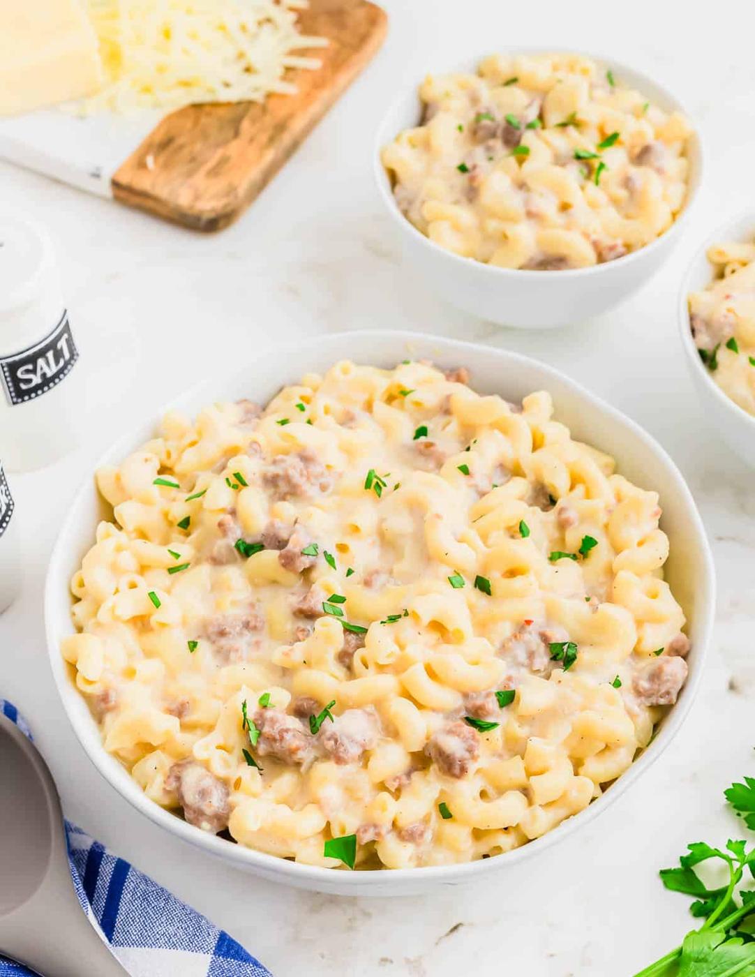 A bowl of macaroni and cheese with sausage and parmesan cheese.