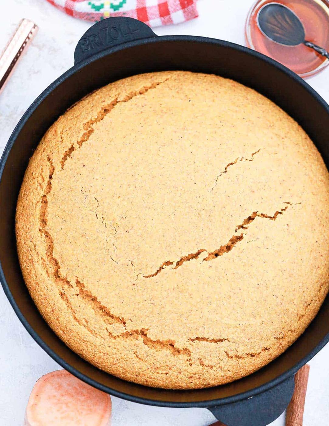 Baked sweet potato cornbread recipe in a black cast iron skillet.