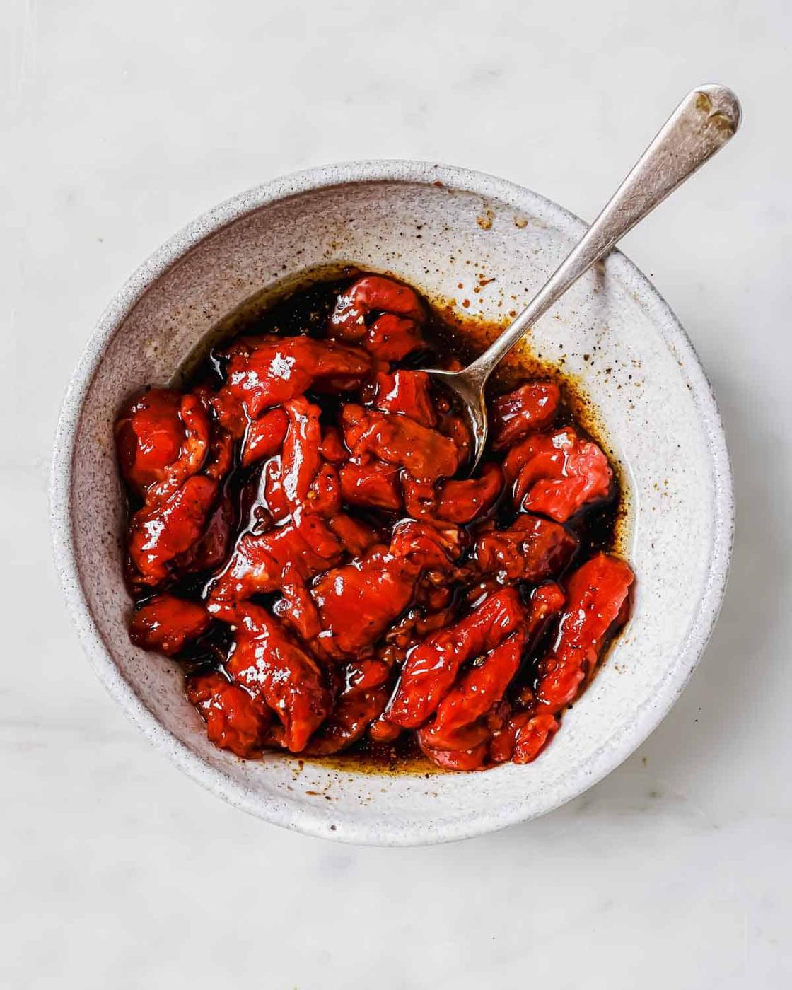 Korean marinated beef in a white bowl with a spoon.