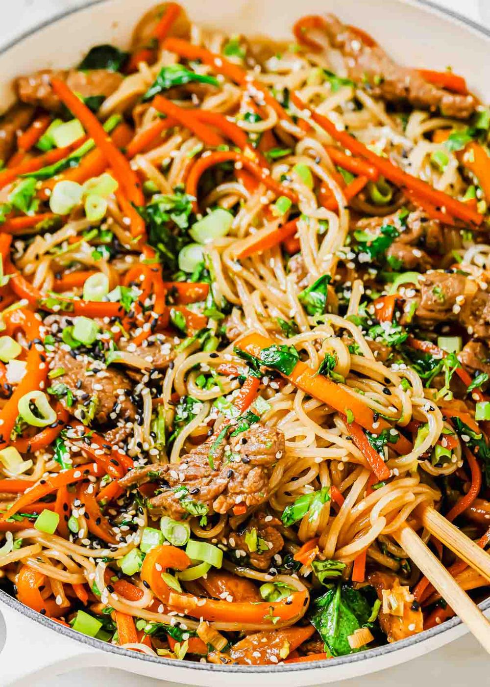 Korean japchae in a pan with chopsticks.