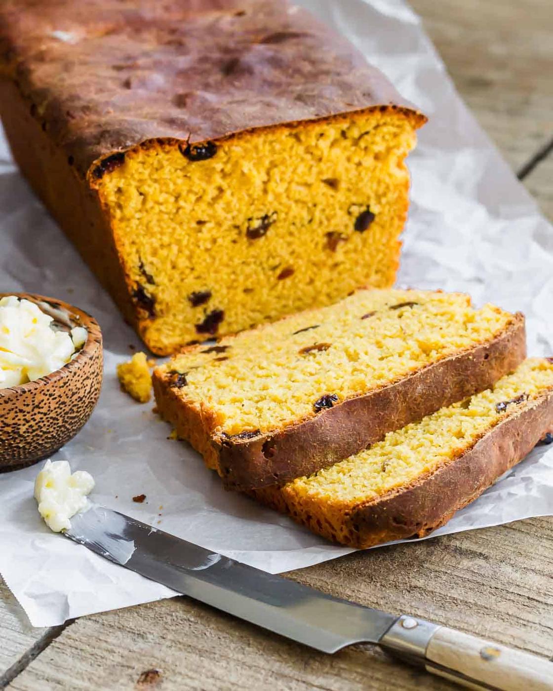 Sweet potato bread loaf with two slices and a knife with some butter on it.