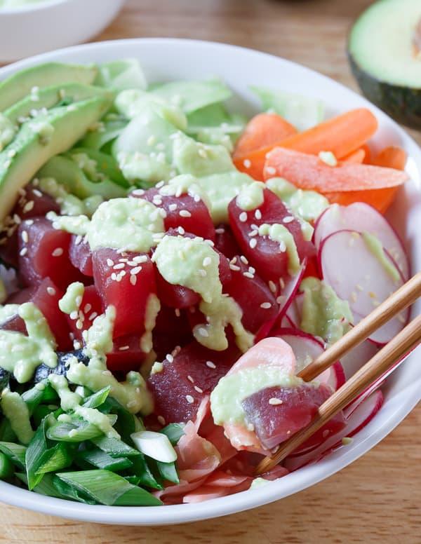A quick and easy tuna sushi bowl packed with radishes, carrots, cucumber, seaweed and avocado then drizzled in a spicy avocado wasabi dressing.