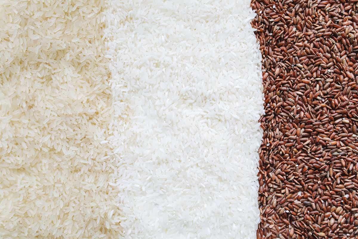 Top view of different types of rice grains arranged in two halves forming a diagonal division on a flat surface.