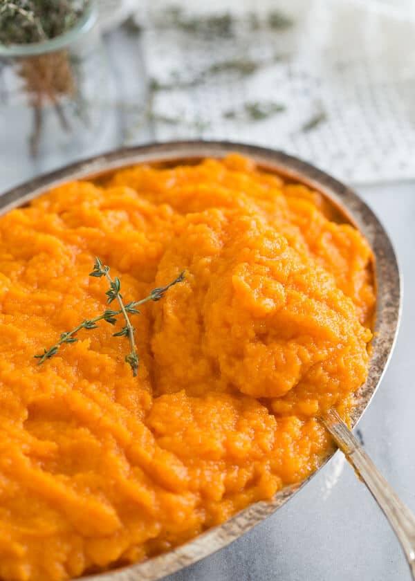 Scooping out a spoonful of parsnip and carrot puree from a serving dish.