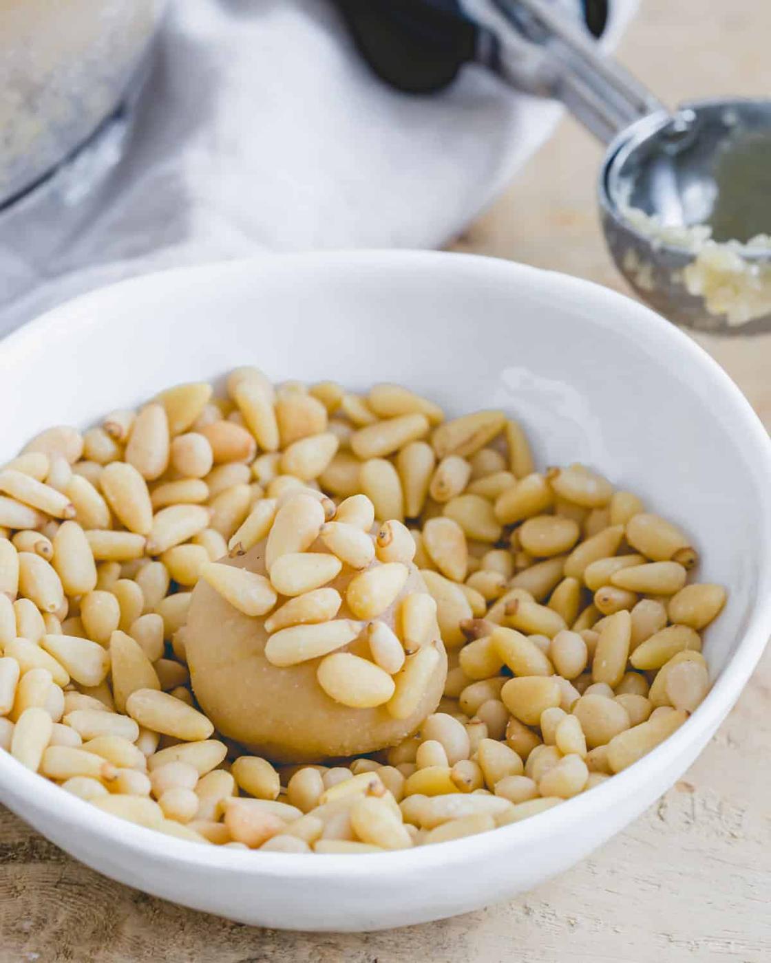Rolling pignoli cookie dough balls in pine nuts.