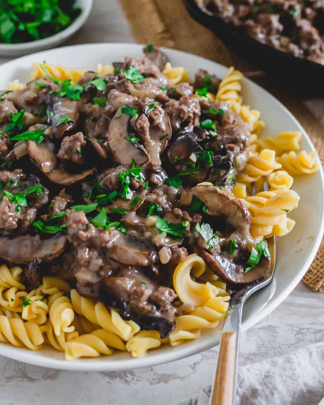 Close up of plated venison stroganoff recipe with a fork.