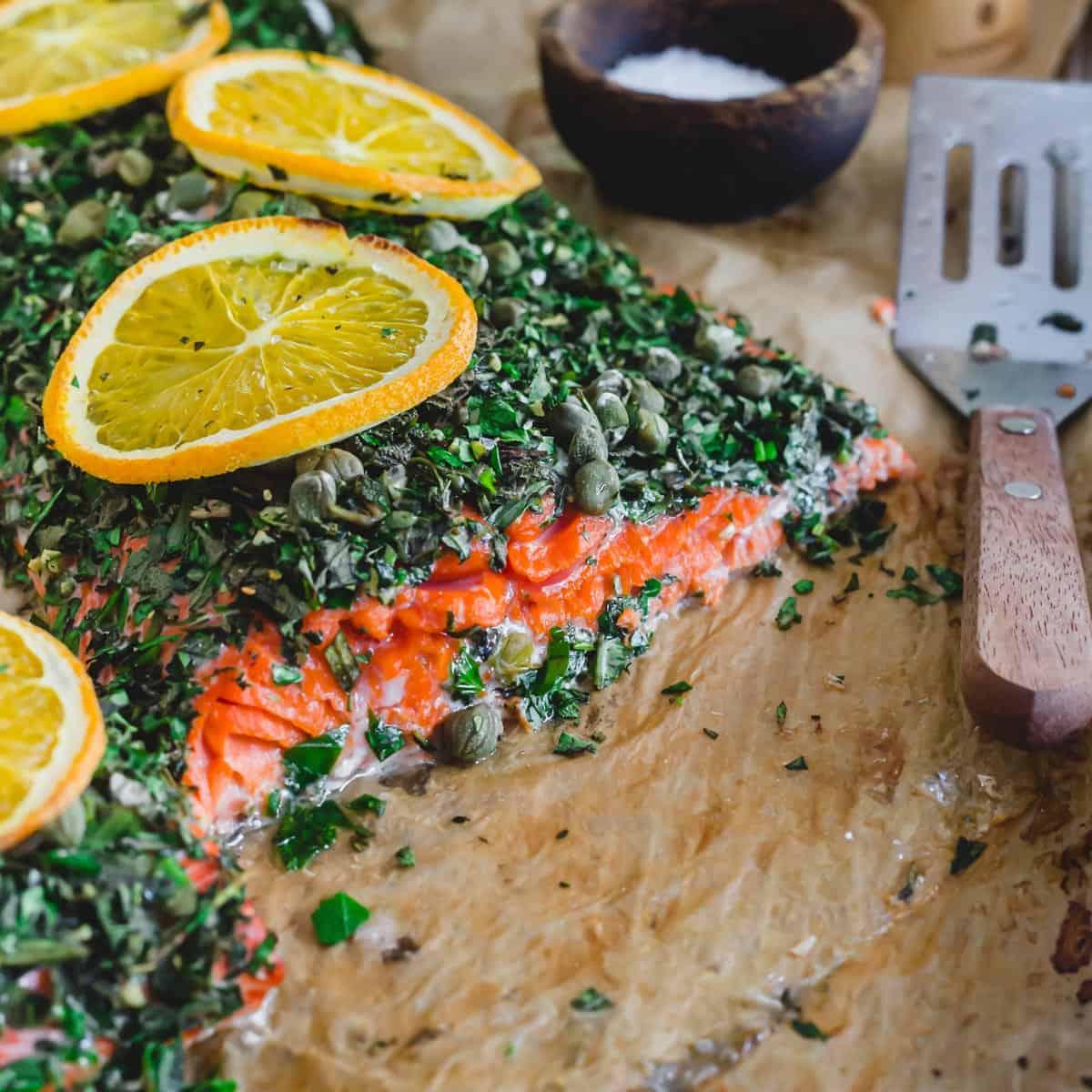 Bright red baked wild sockeye salmon with an herb crust on a baking sheet with spatula for serving.