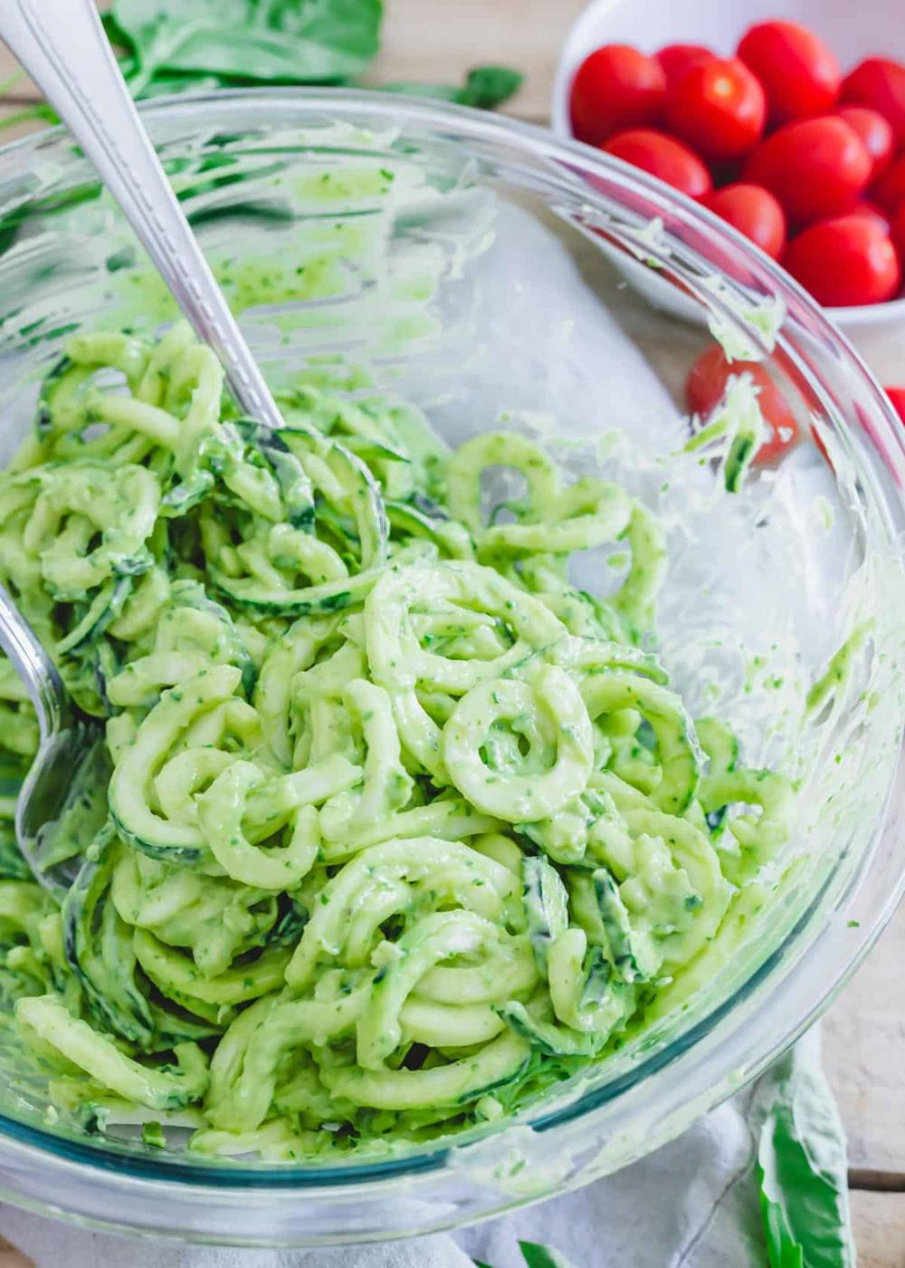 Zucchini pasta spirals tossed with an avocado cream sauce in a glass bowl.