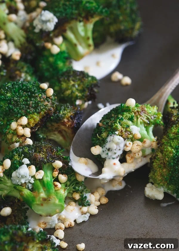 A beautifully plated dish of Grilled Broccoli with blue cheese sauce and crisps, showcasing the vibrant colors and textures from Girl and the Goat restaurant in Chicago, IL