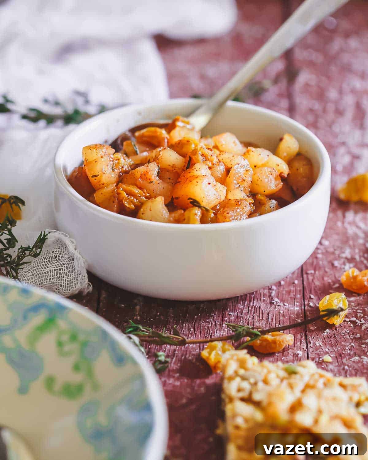 Apple Compote Delights 2 A bowl of cooked apple compote seasoned with herbs and spices, with a spoon in the bowl.