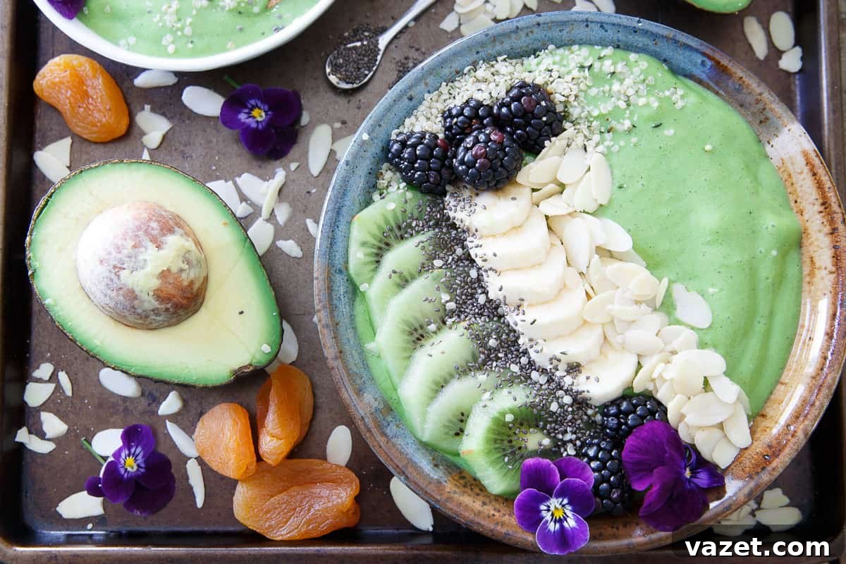 Why Drink Your Smoothie When You Can Enjoy This Avocado Pineapple Bowl with Endless Toppings! A vibrant green avocado pineapple smoothie bowl generously loaded with a variety of healthy toppings including nuts, seeds, and fresh fruit.