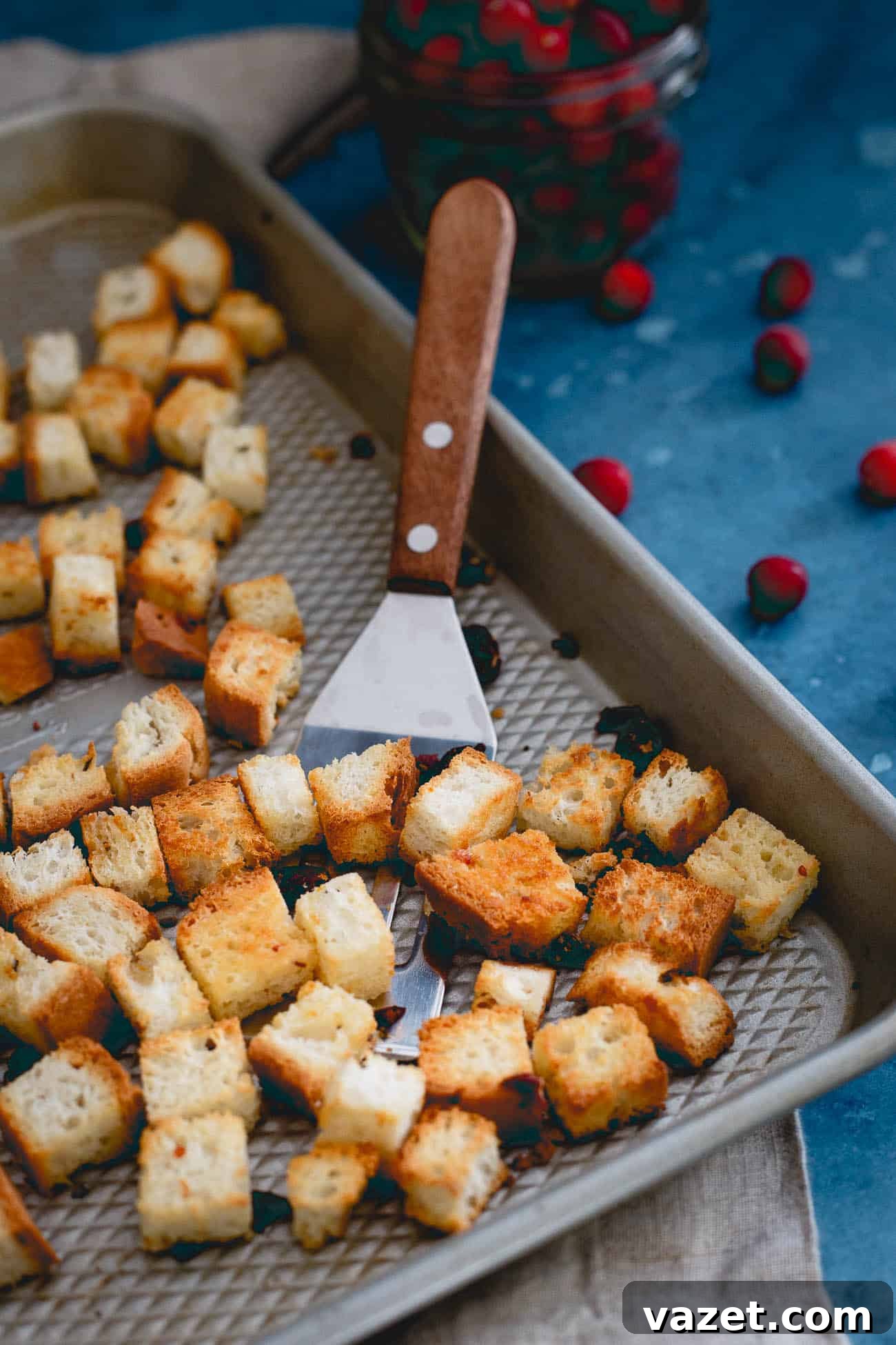 Freshly baked homemade croutons cooling on a pan with a spatula, ready to be added to the broccoli salad.