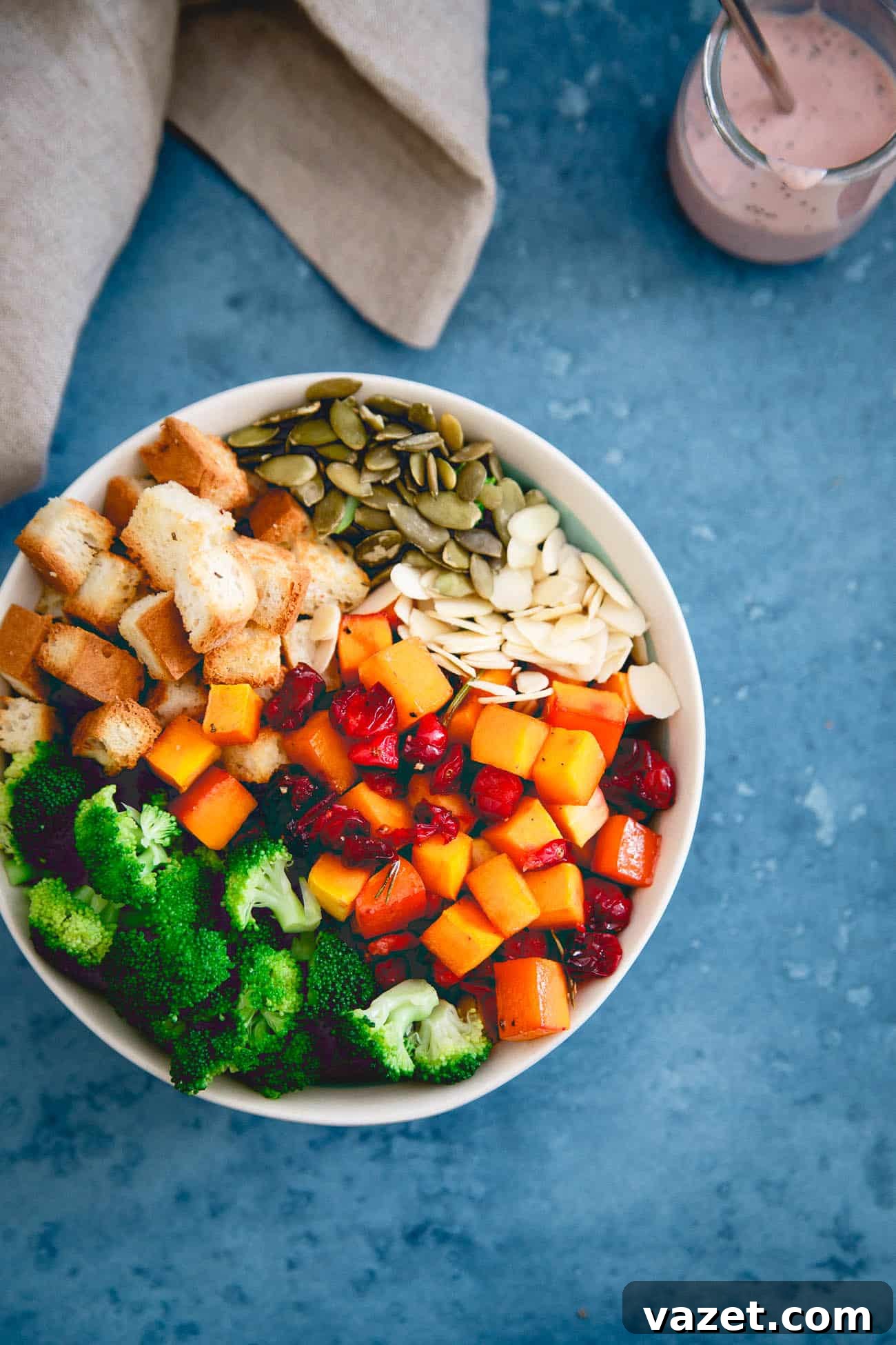 A large mixing bowl filled with crisp broccoli florets, roasted butternut squash, and cranberries, before tossing with dressing.