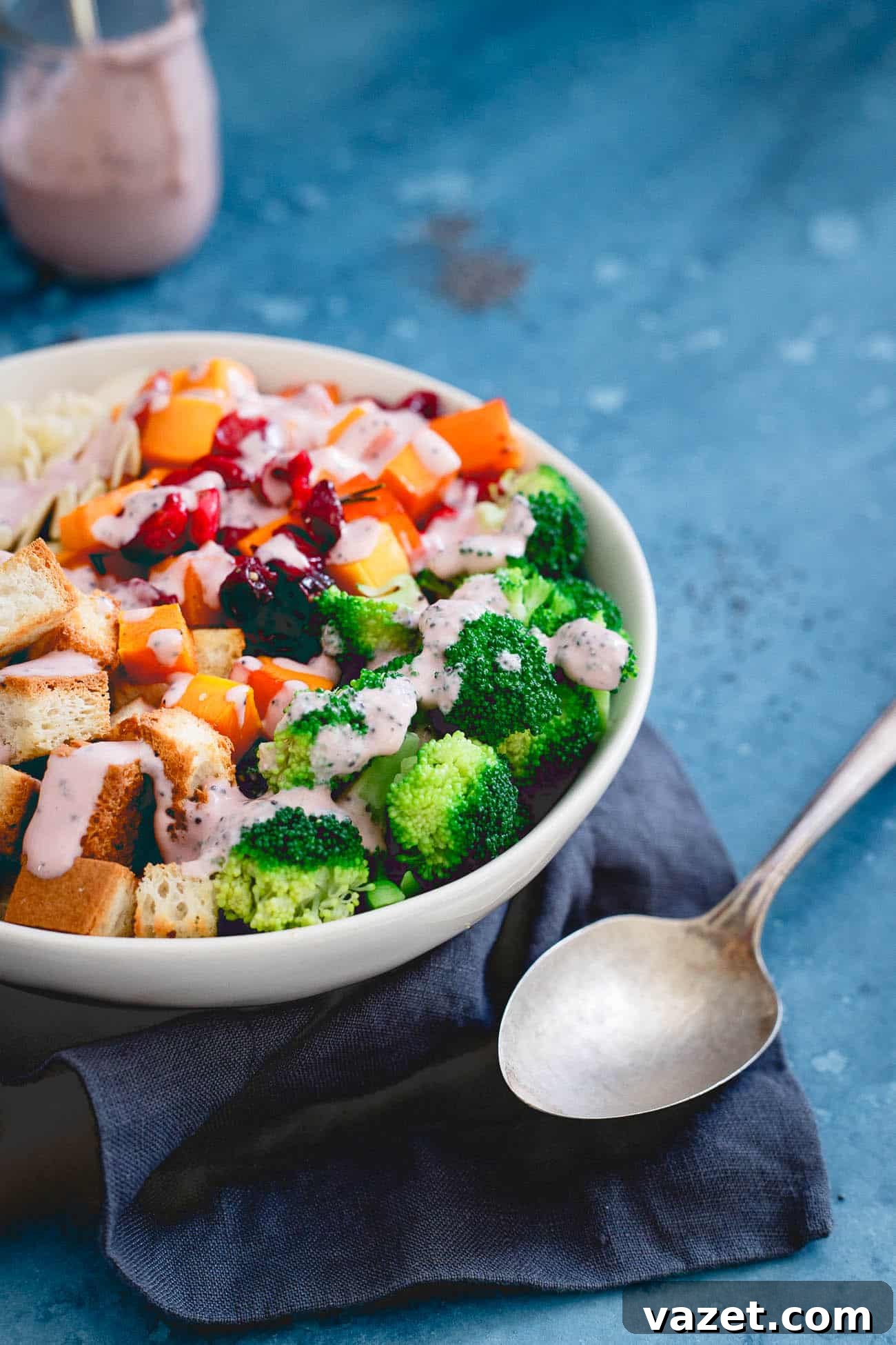 A pristine white bowl filled with the roasted cranberry broccoli salad, elegantly presented with a spoon on the side.