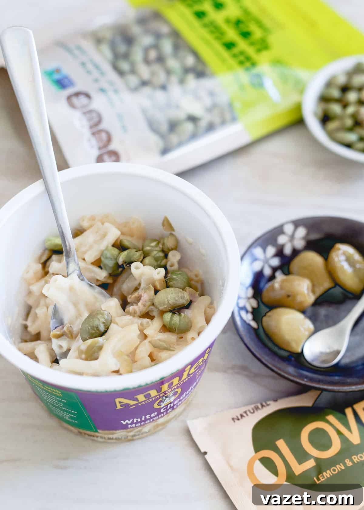 A healthy, savory afternoon snack idea featuring Annie's mac and cheese cups, Oloves lemon rosemary olives, and sea salt dried edamame, all available at CVS.