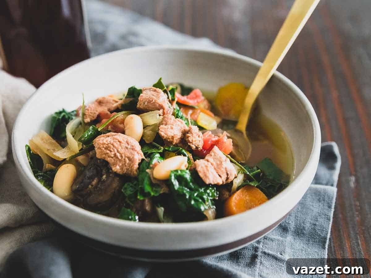 A lamb stew slow cooker recipe with hearty white beans, mushrooms, kale, tomatoes and carrots flavored with fresh rosemary.