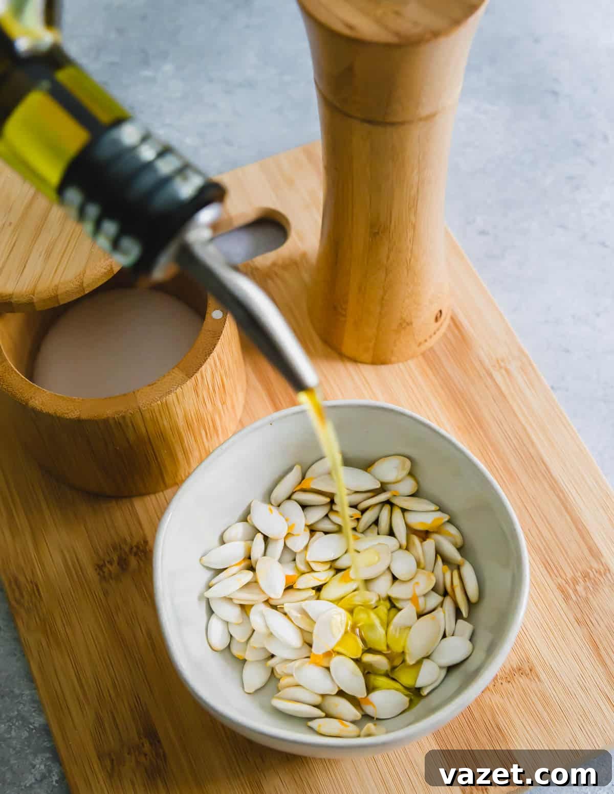 cleaned squash seeds being tossed with extra virgin olive oil cleaned squash seeds being tossed with extra virgin olive oil