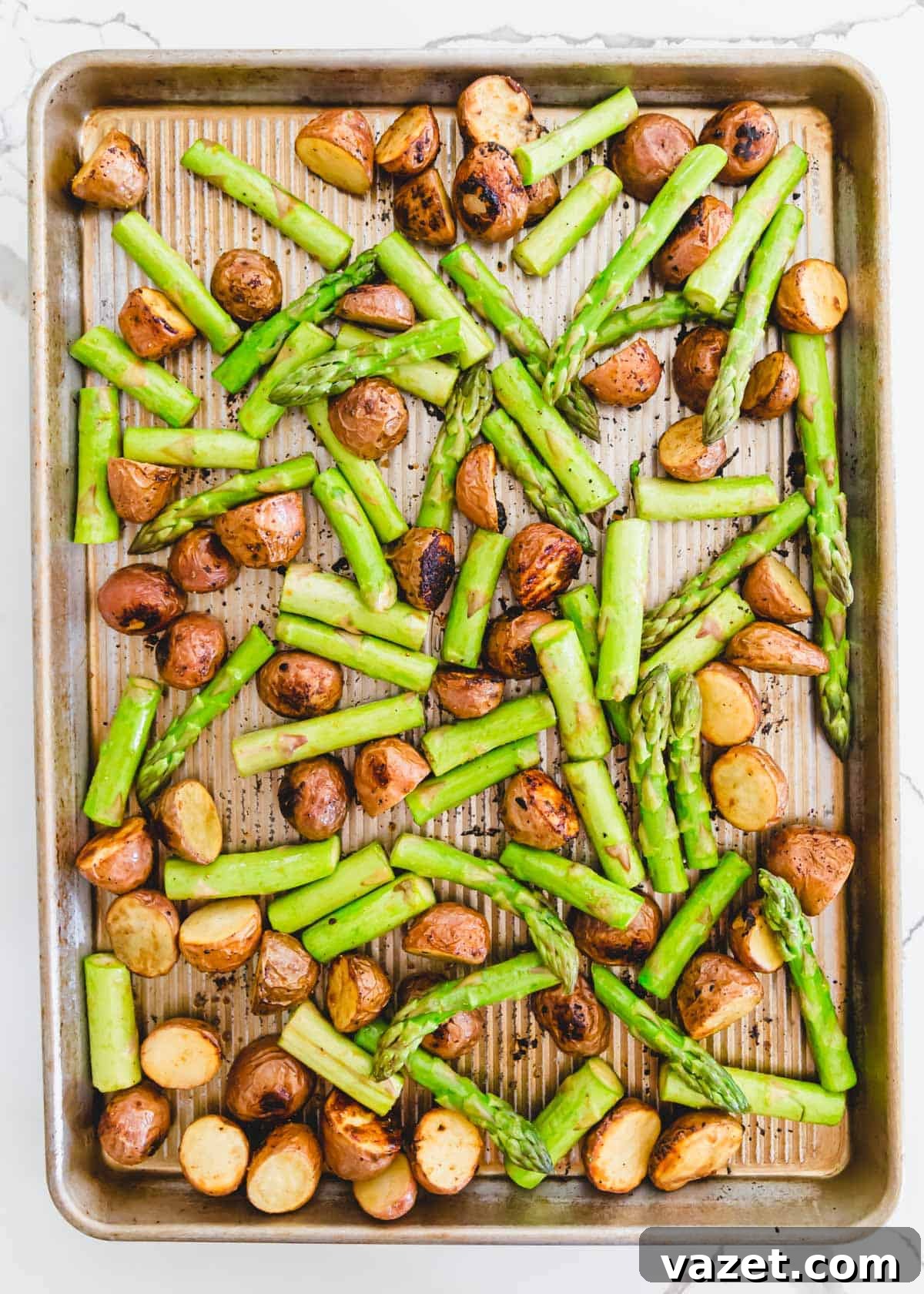 Roasted red potatoes with fresh asparagus spears on a baking sheet Roasted red potatoes with fresh asparagus spears on a baking sheet