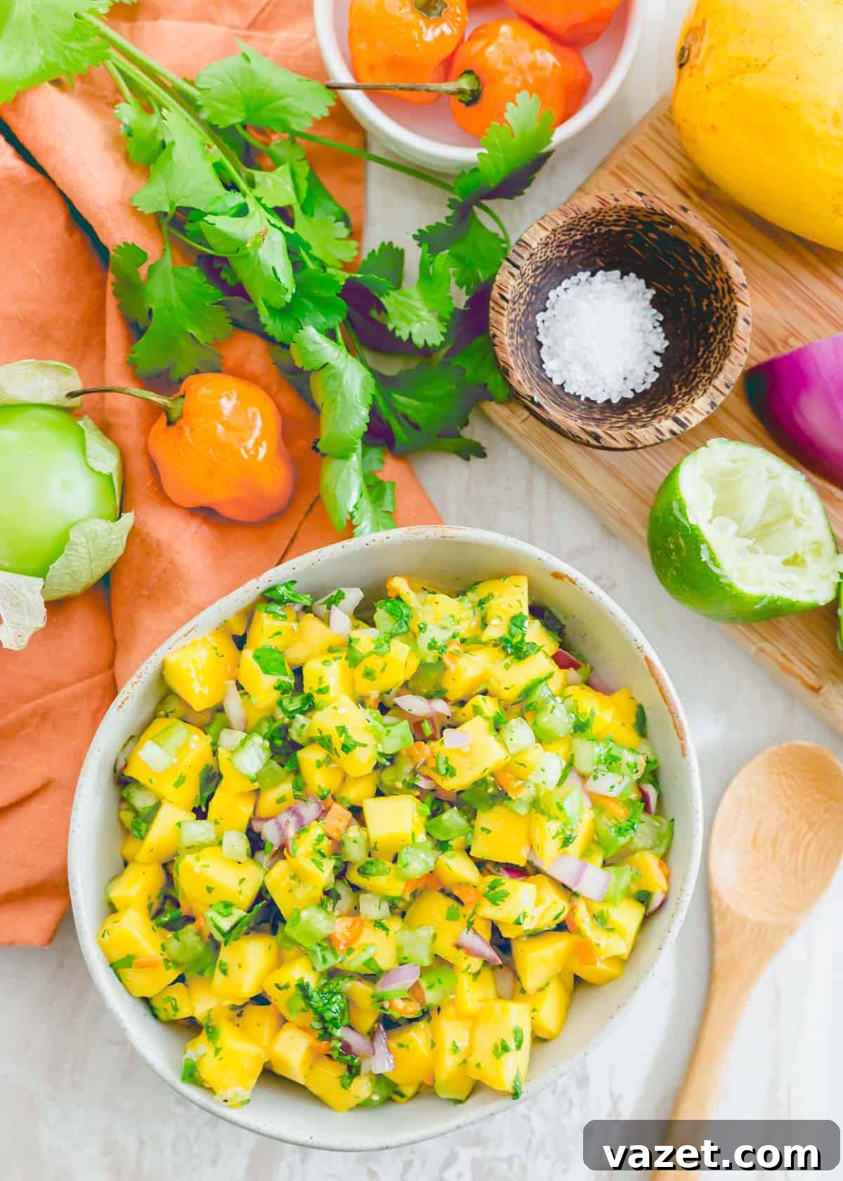 A bowl of freshly prepared mango habanero salsa with a serving spoon nestled on the side, inviting to be tasted.