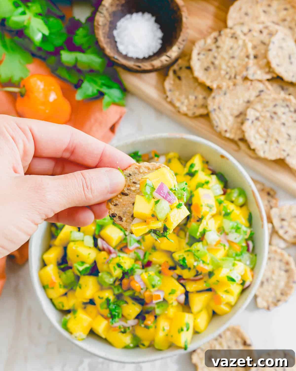 A cracker topped with a generous spoonful of mango habanero salsa, showcasing the chunky texture and vibrant colors of the fresh ingredients.