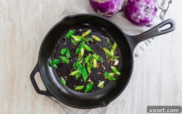 Scallions and garlic sautéing in bacon fat in a skillet.