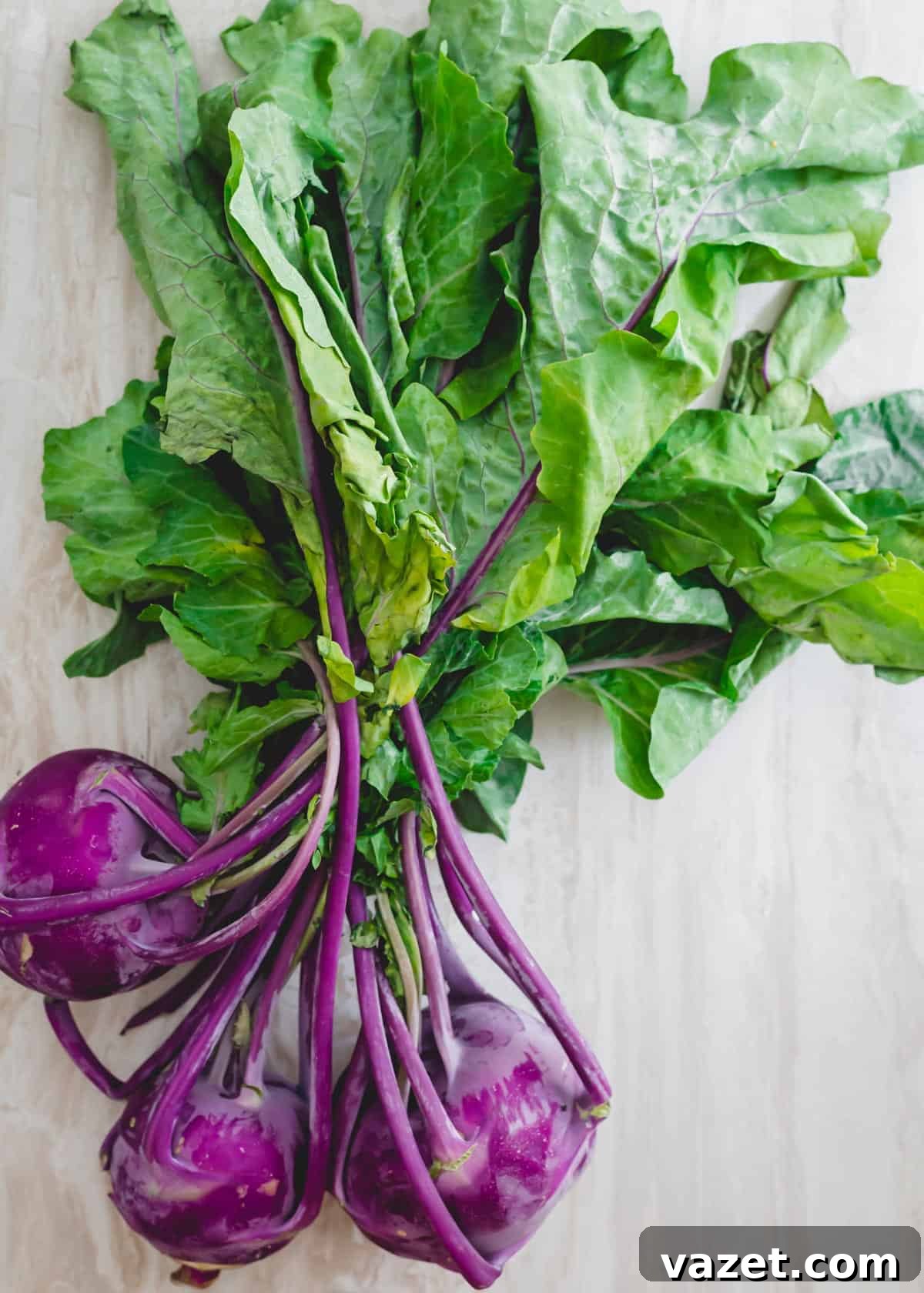 Purple kohlrabi with greens attached. A fresh purple kohlrabi bulb with its healthy, green leaves still attached, showcasing the entire vegetable.