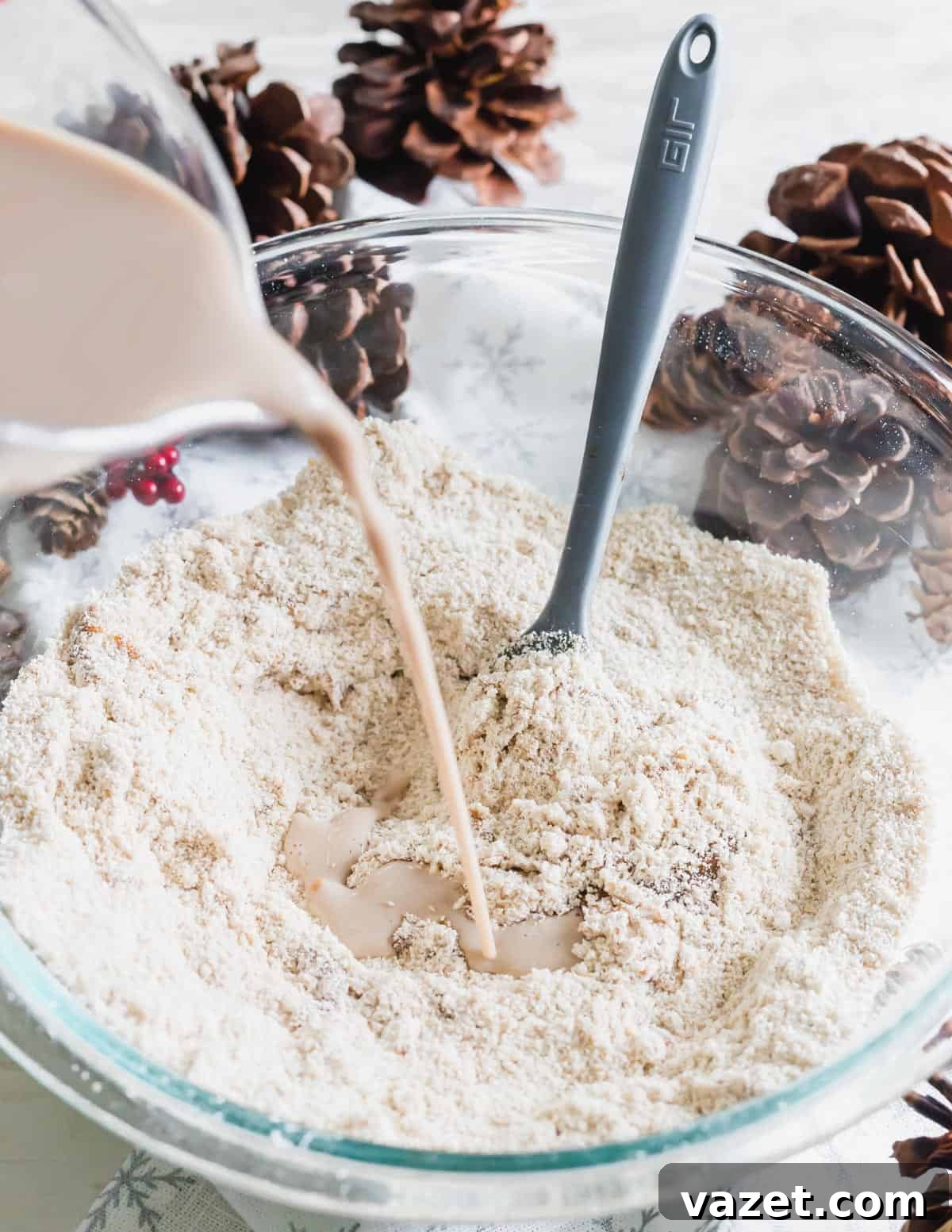 Milk being poured into a bowl of dry ingredients including oat and almond flour, spices, and baking powder for gingerbread waffles.