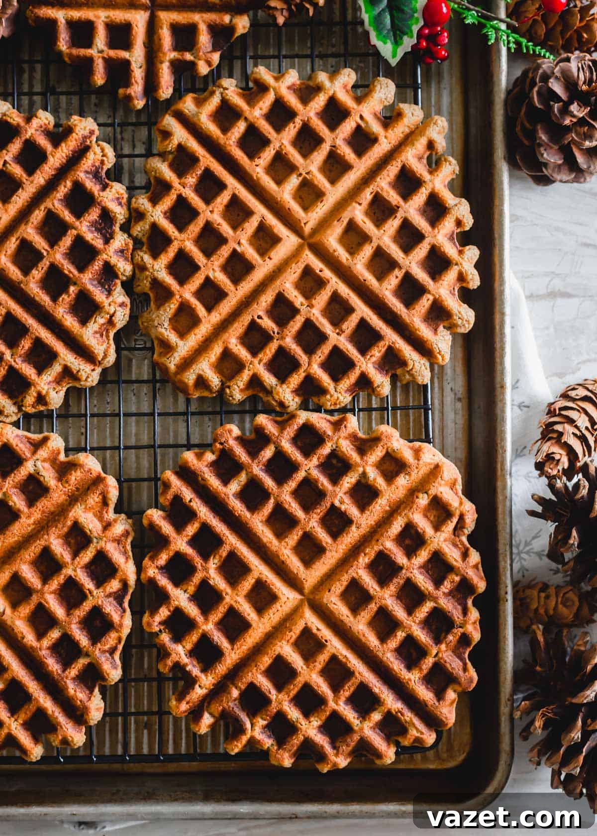 A stack of golden brown, gluten-free and vegan gingerbread waffles cooling on a wire rack.