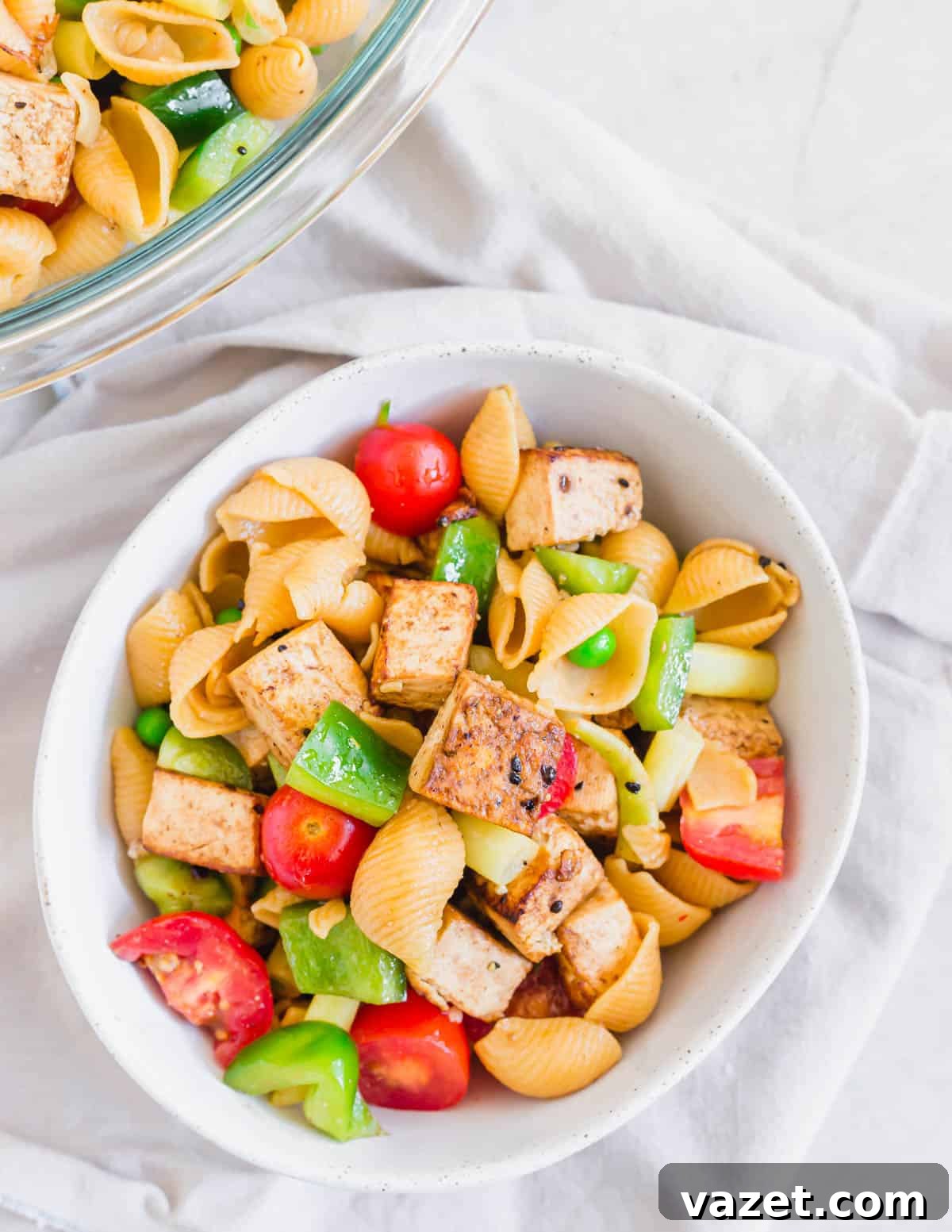 Protein-Packed Tofu Pasta Salad for a Healthy Meal Tofu pasta salad in a bowl on a neutral colored napkin, showcasing a vibrant mix of pasta, crispy tofu, and fresh vegetables.