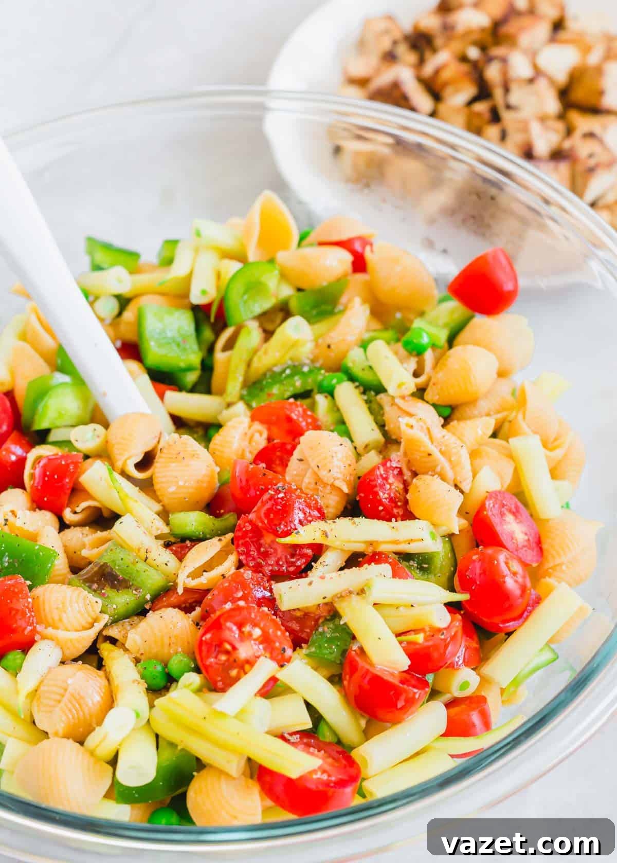 Gathered Ingredients for Tofu Pasta Salad Preparation Cooked pasta, cherry tomatoes, yellow wax beans, peas, and green bell peppers are gathered in a large glass mixing bowl, ready for the dressing and tofu.