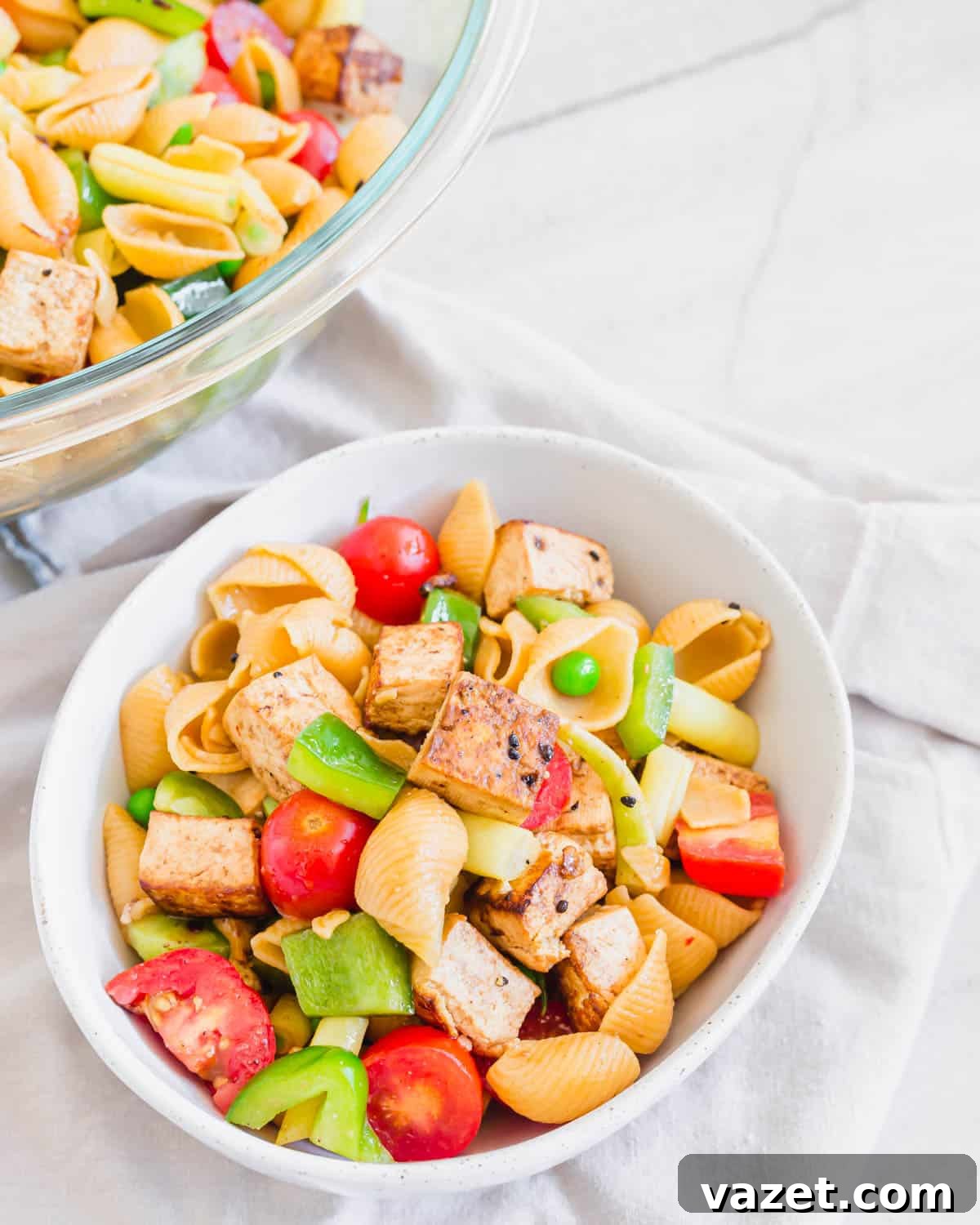 Ready-to-Serve Tofu Pasta Salad A vibrant and healthy Tofu Pasta Salad served in a white bowl with a larger serving bowl in the background, ready to be enjoyed.