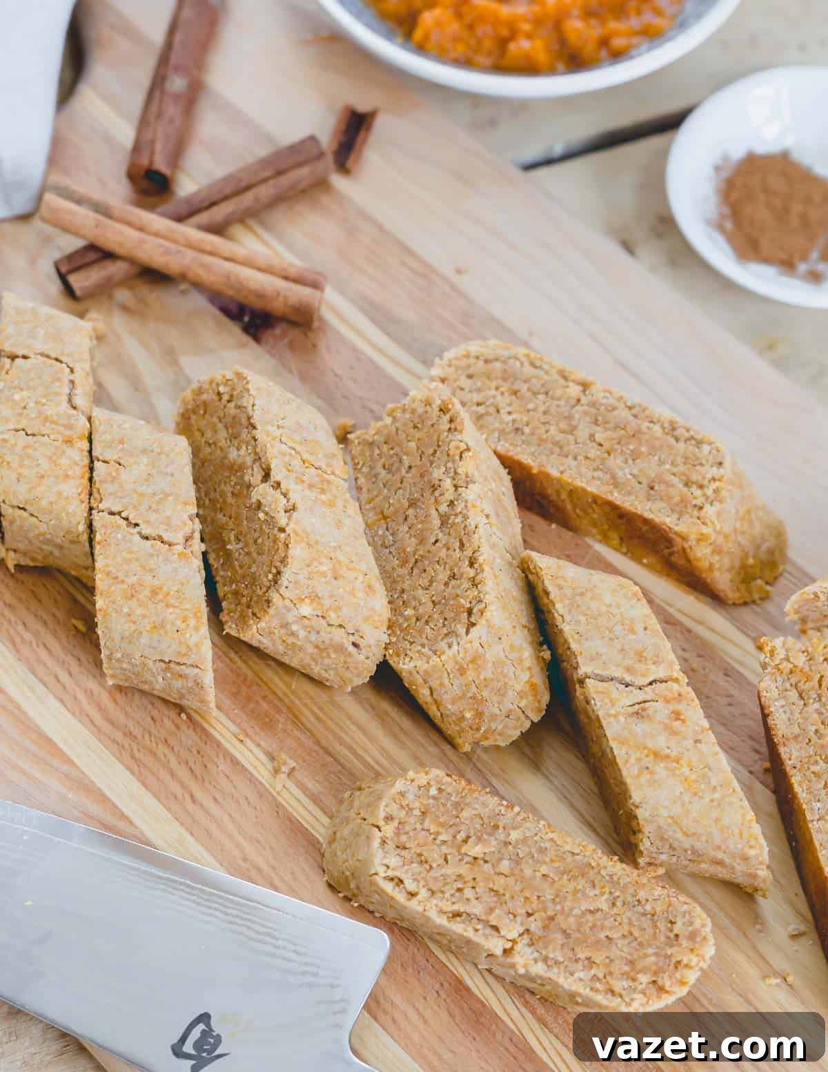 Pumpkin biscotti sliced into cookies after the first bake on a wooden cutting board.