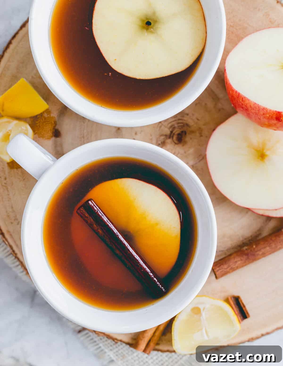 Pure Autumn Comfort: Non-Alcoholic Apple Cider Tea Non-alcoholic warm apple cider black tea with a cinnamon stick and round apple slice in a white mug, ready to be enjoyed.