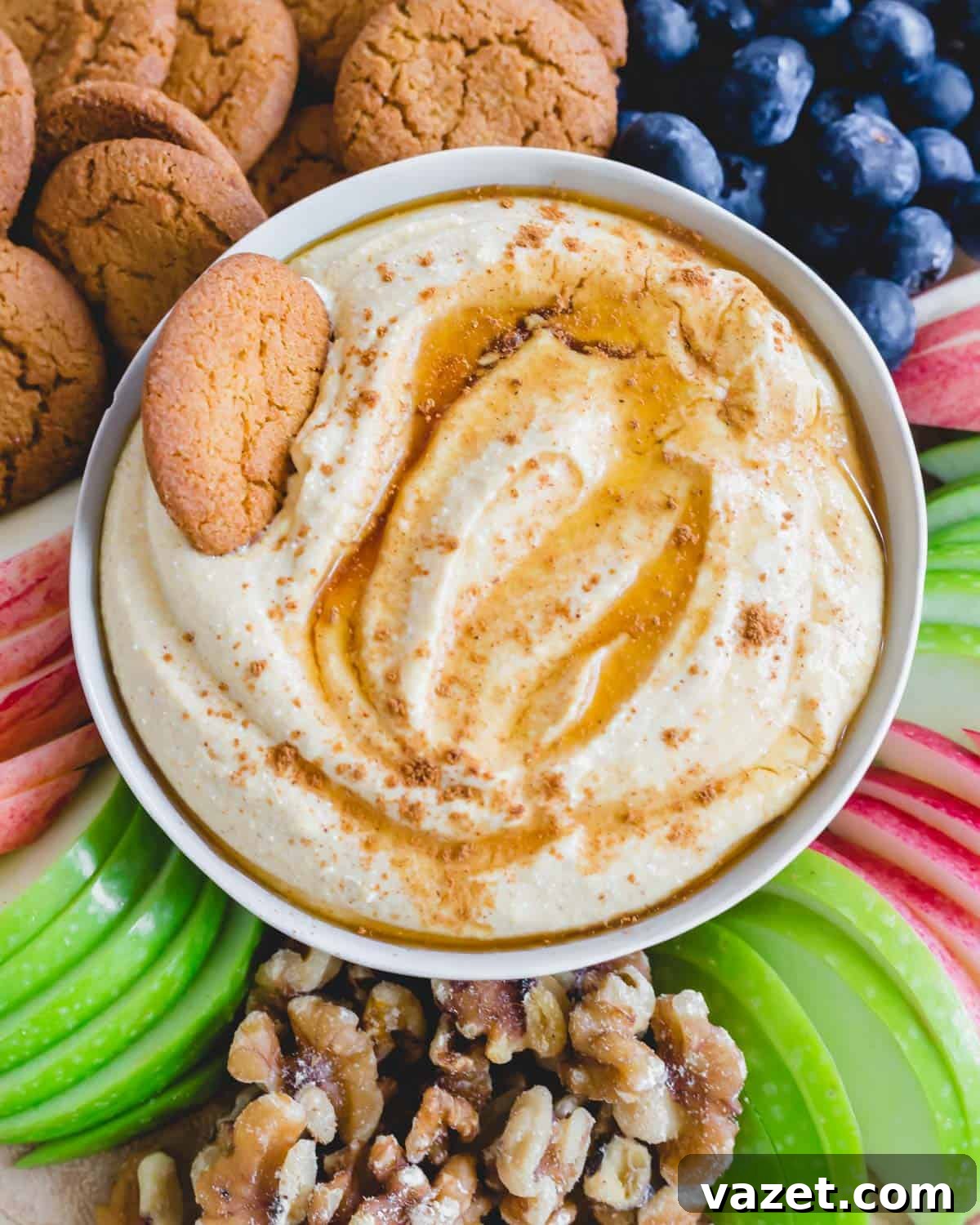Sweet whipped ricotta dip in a bowl with fruit and gingersnaps around it, beautifully presented for a fall gathering.