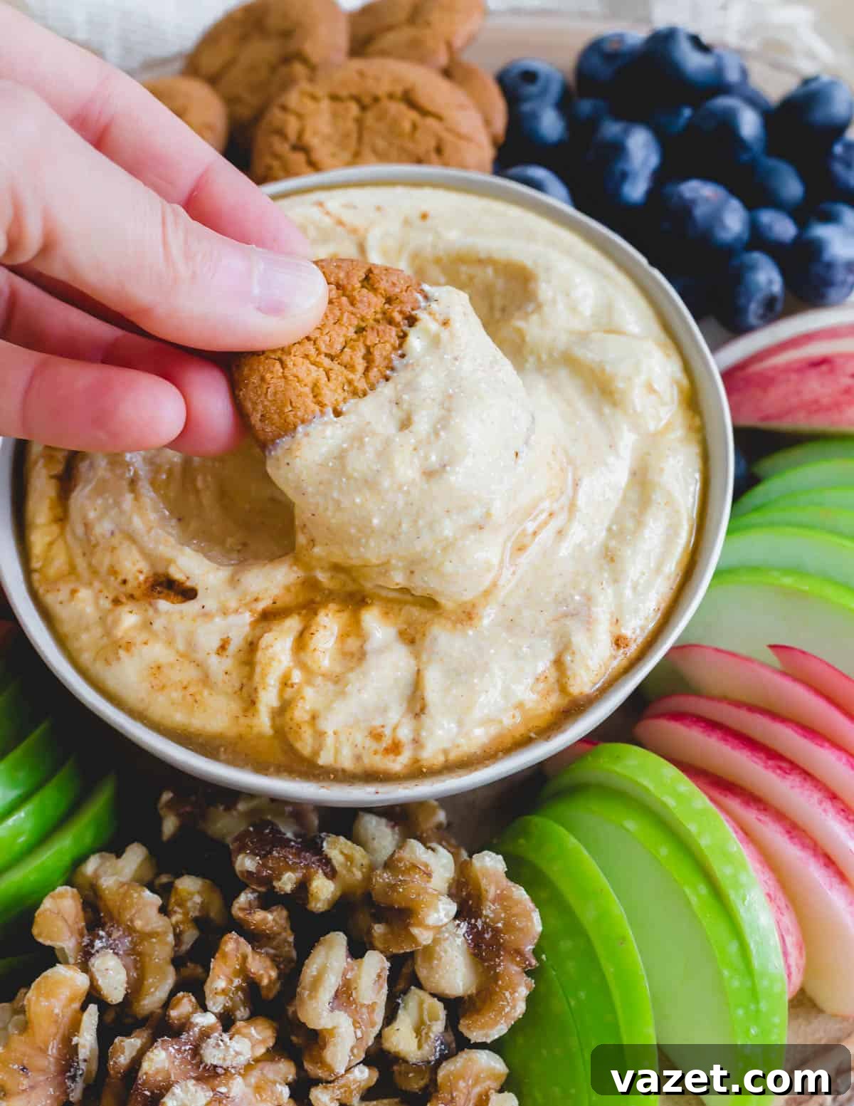 A gingersnap cookie being dipped into a luscious sweet ricotta dip, highlighting the creamy texture.