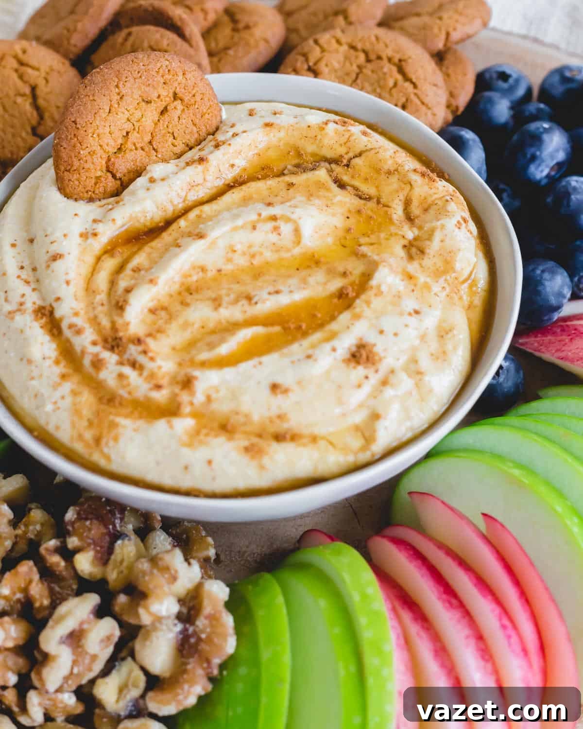 Pumpkin ricotta dip in a bowl with a gingersnap cookie resting on the side, ready for dipping.