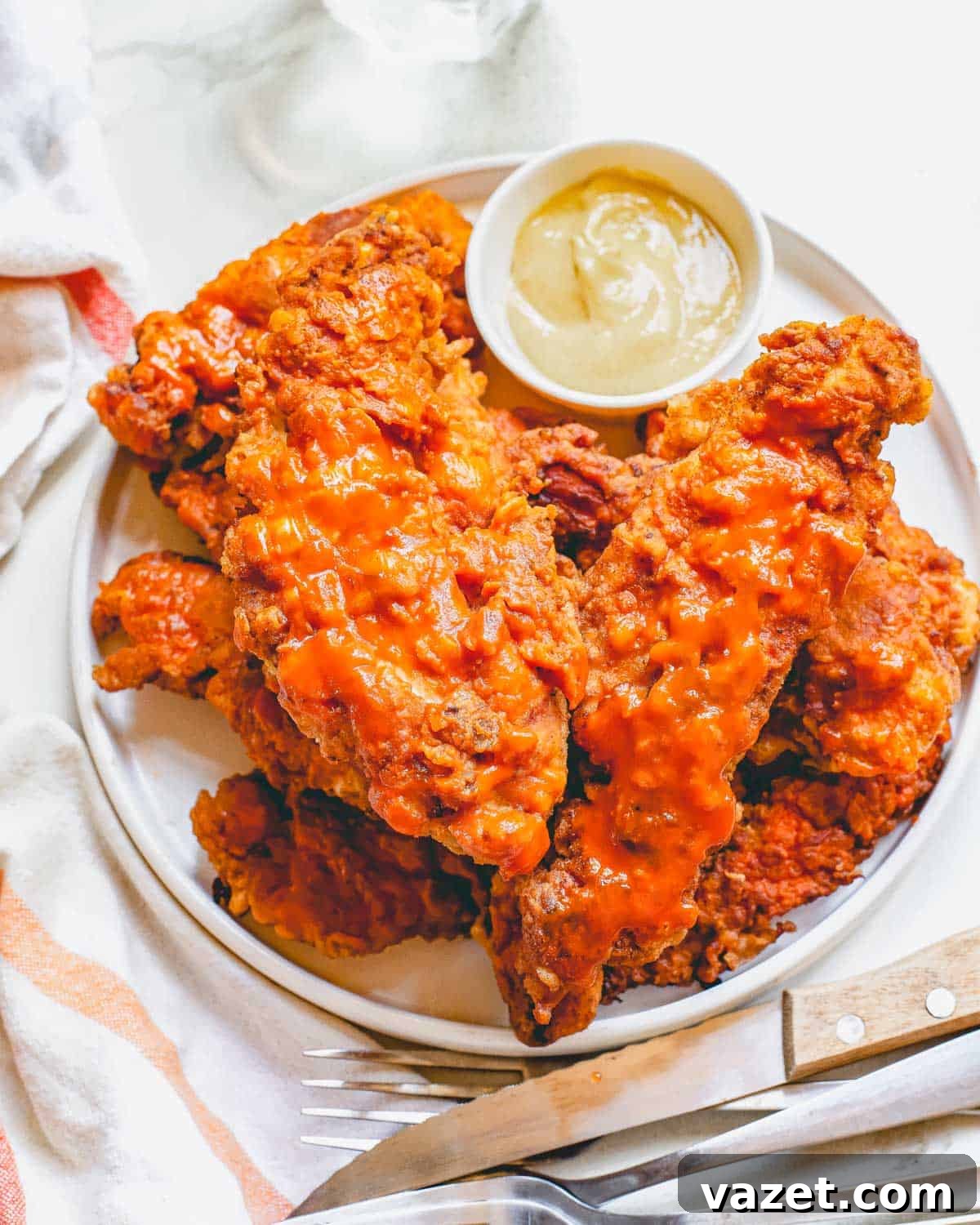 Crispy Air Fryer Buffalo Chicken Tenders Served with Dipping Sauce Air fryer buffalo chicken tenders on a white plate with dipping sauce in a small bowl, showcasing their crispy texture.