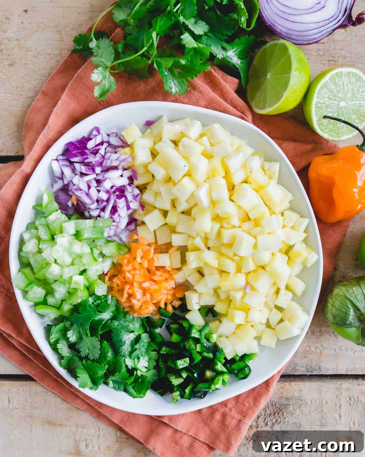 Prepped ingredients to make pineapple salsa with habanero pepper on a white plate. Prepped ingredients to make pineapple salsa with habanero pepper on a white plate.