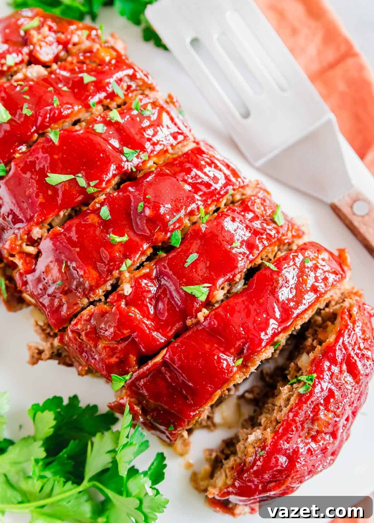Close up of sliced bomb meatloaf recipe on a serving platter garnished with chopped parsley. A close-up view of generous slices of bomb meatloaf on a white serving platter, beautifully garnished with fresh chopped parsley, highlighting the tender interior and glossy glaze.