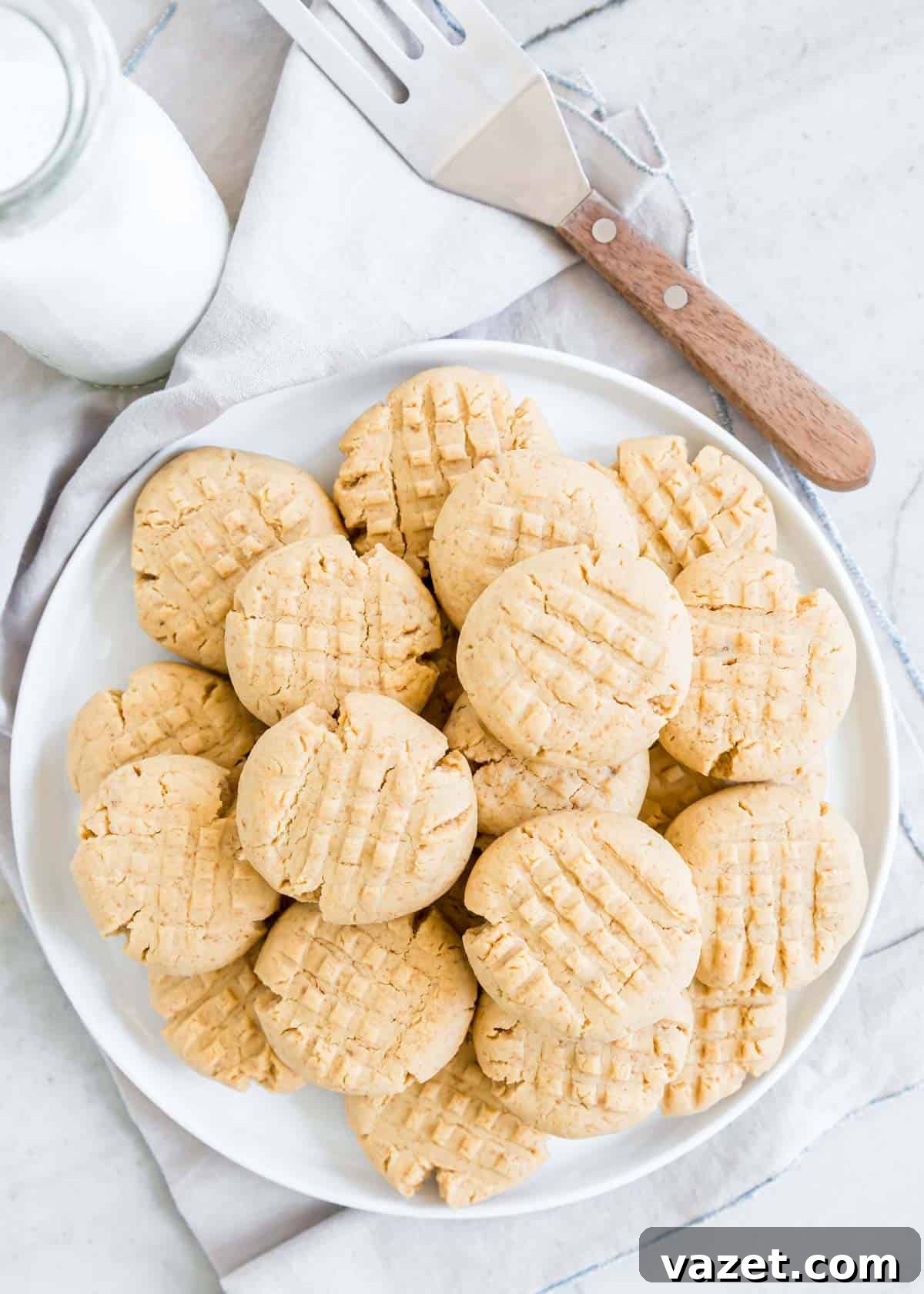 Flourless Peanut Butter Delights 7 Gluten free peanut butter cookies on a white plate with milk and spatula on the side.