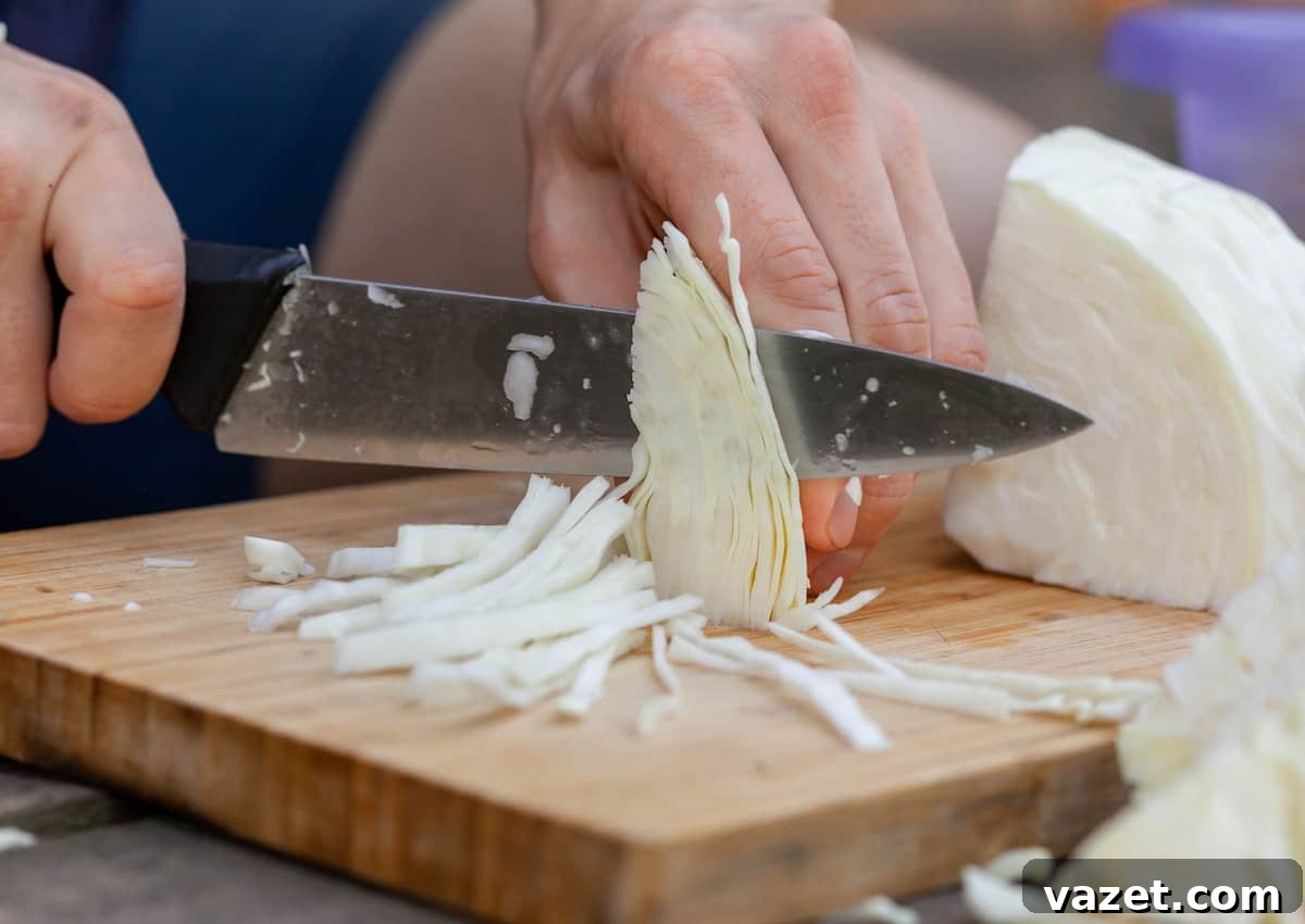 The Ultimate Guide to Freezing Cabbage 5 A person thinly slicing cabbage on a wooden cutting board, preparing it for cooking.
