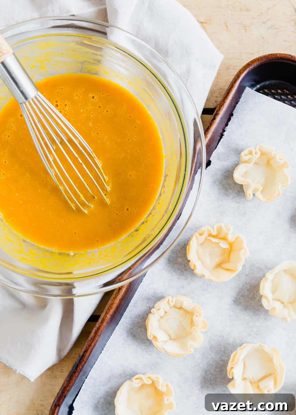 Bite-Sized Pumpkin Delights 3 Smooth pumpkin pie batter in a glass mixing bowl, with rows of empty mini phyllo dough shells on a baking sheet, ready for filling.