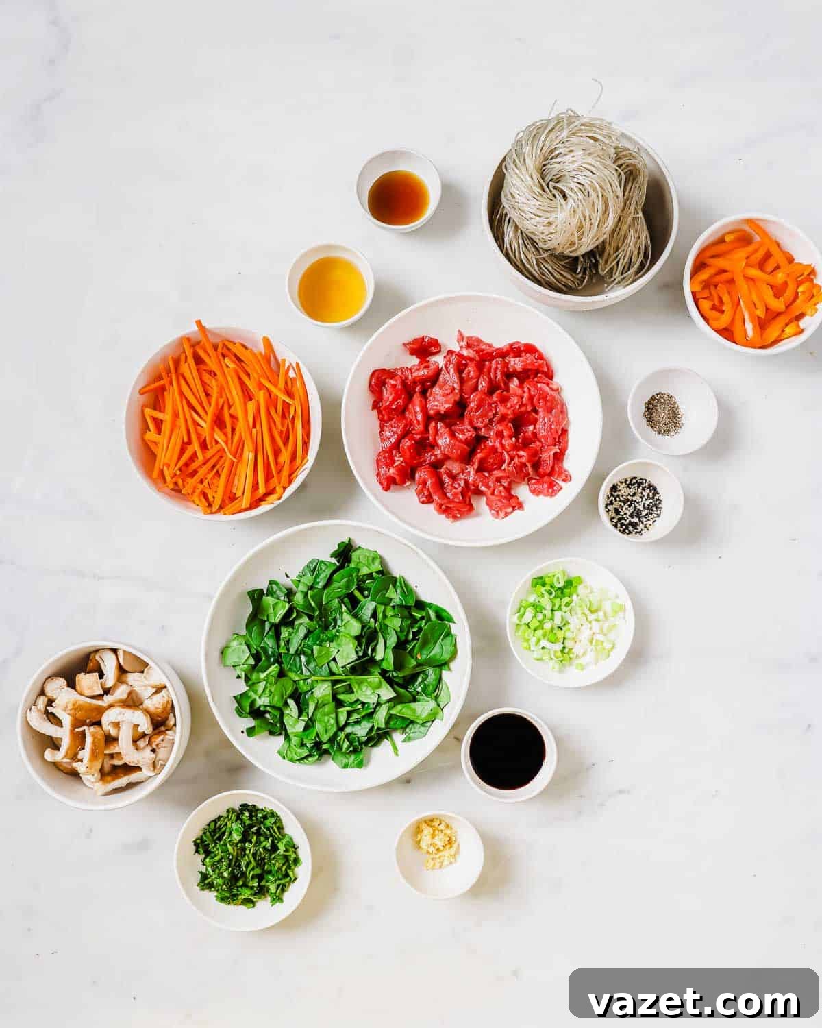 A vibrant selection of fresh ingredients, including sliced bell peppers, carrots, shiitake mushrooms, green onions, and fresh spinach, ready to be prepared for the sweet potato glass noodle dish.