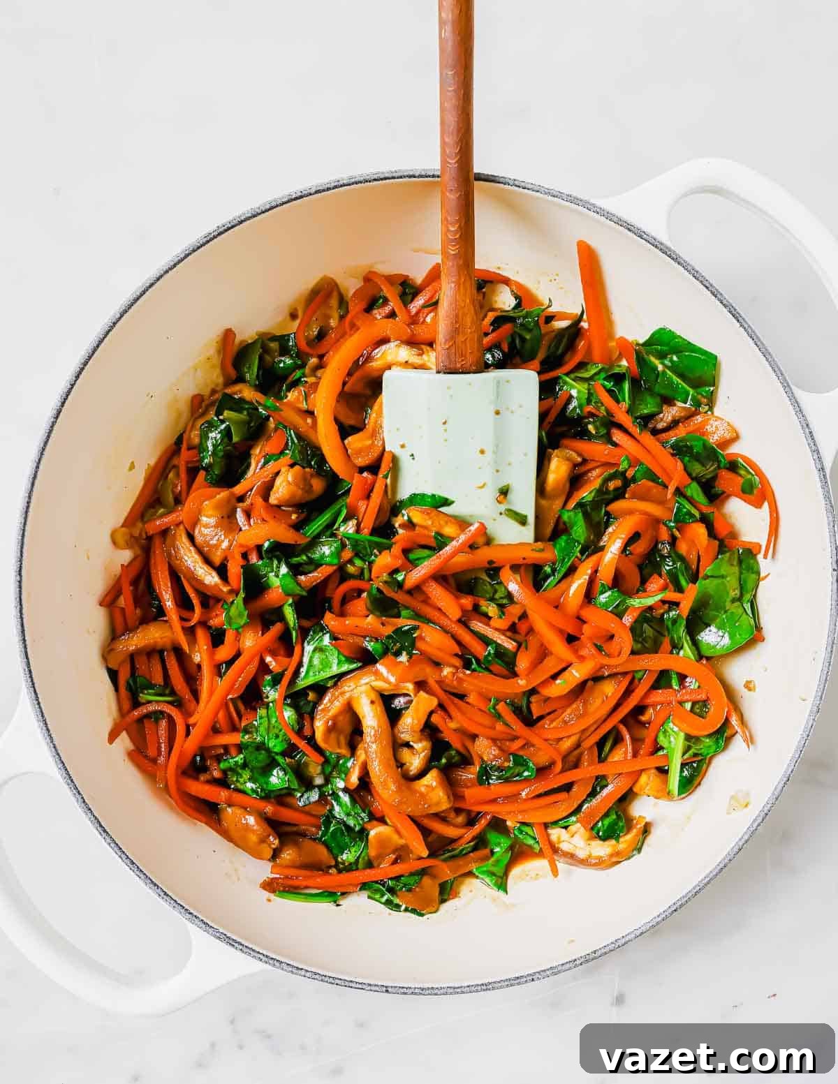 A colorful mix of sliced bell peppers, shiitake mushrooms, and fresh spinach sautéing in a skillet with a spatula, showcasing the stir-frying process.