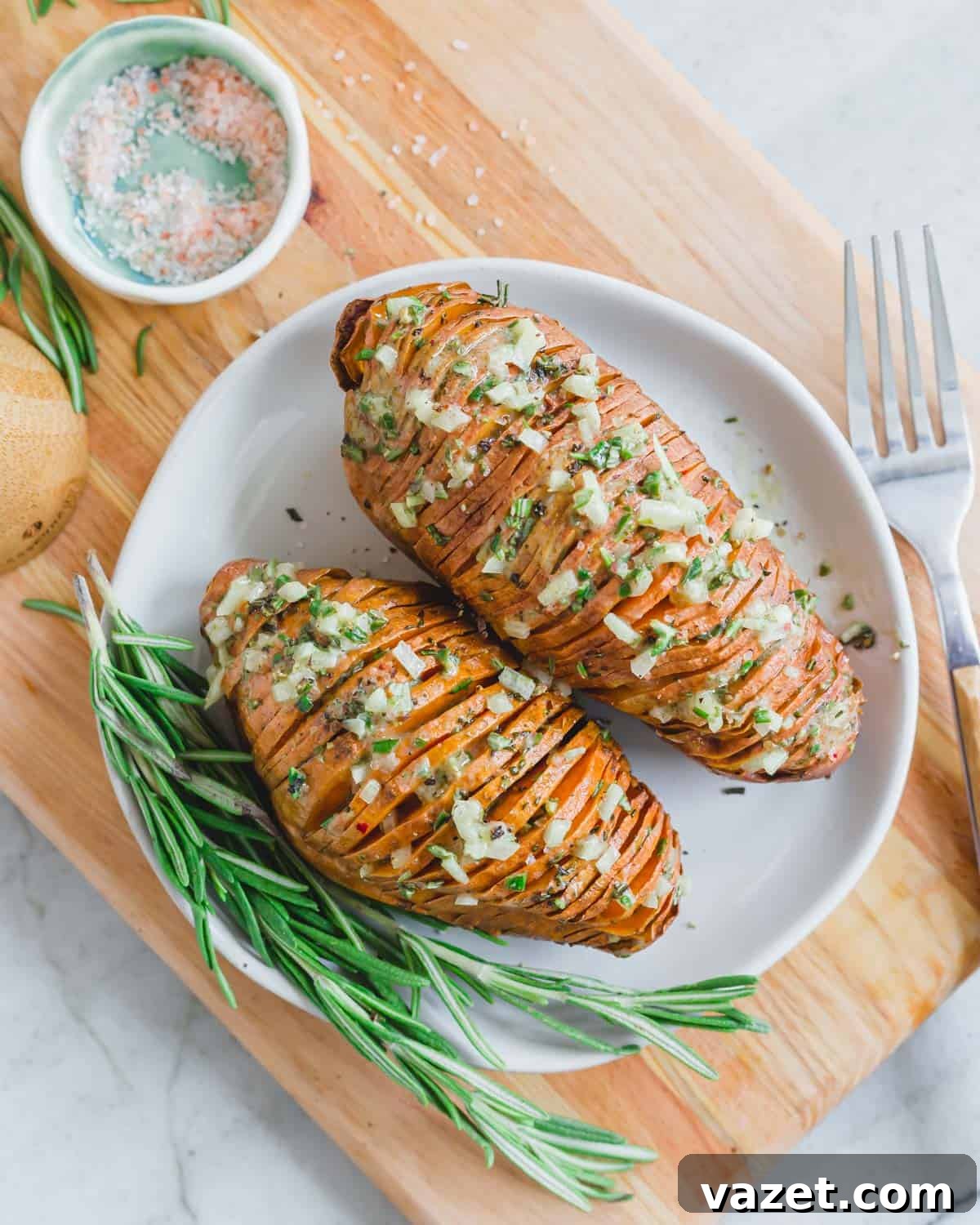 Baked hasselback sweet potatoes on a small plate with rosemary dressing. Baked hasselback sweet potatoes on a small plate with rosemary dressing.