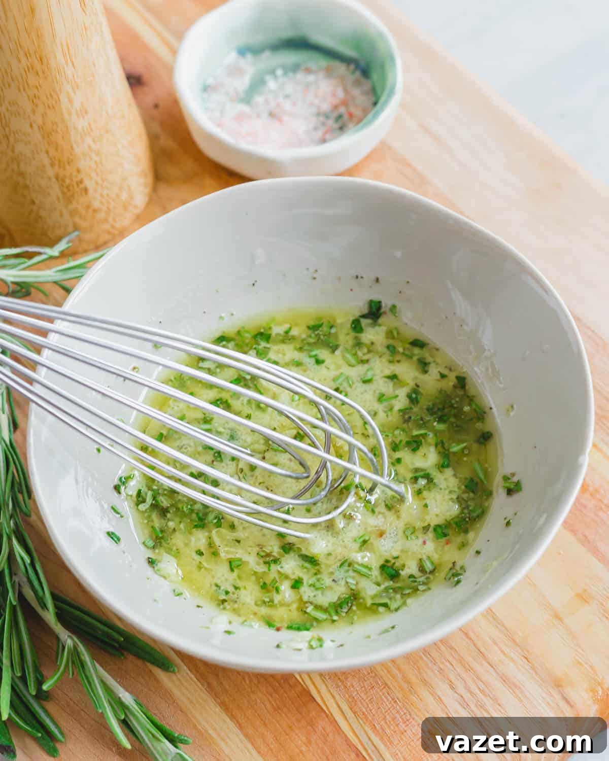 A rosemary mustard vinaigrette dressing in a small bowl with a whisk. A rosemary mustard vinaigrette dressing in a small bowl with a whisk.